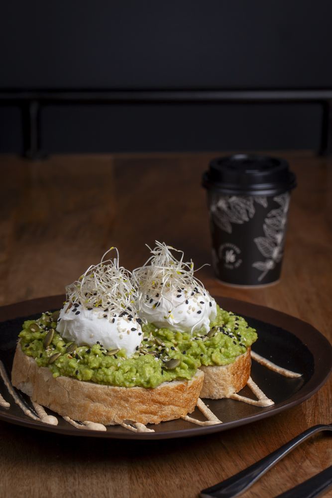 Tostada de pan de masa madre con palta y huevos pochados, con café